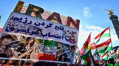 متظاهرون يرفعون لافتة احتجاجية وأعلام إيرانية وكردية في مسيرة لدعم المظاهرات في إيران
